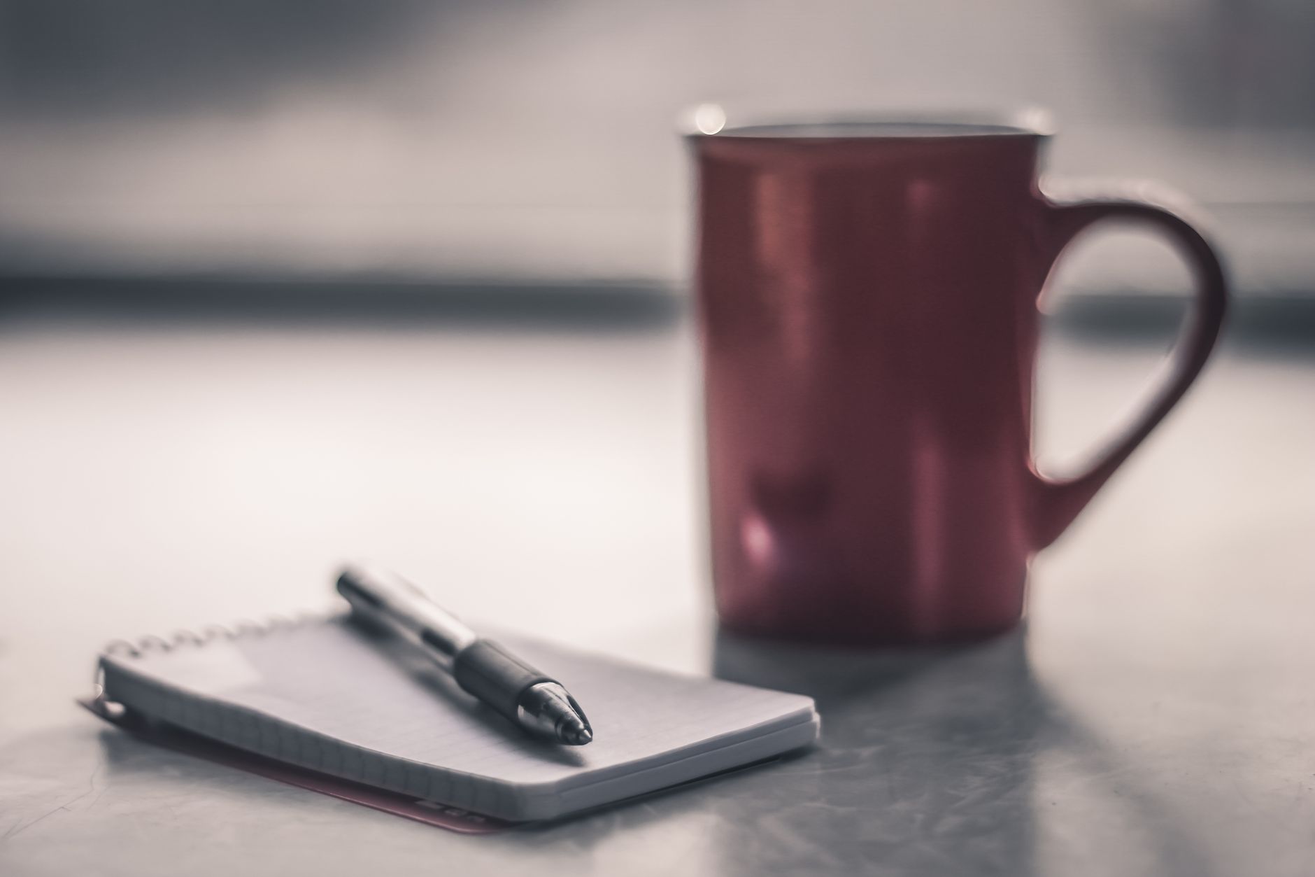 Notesbog og kaffe på et skrivebord, tidlig morgen